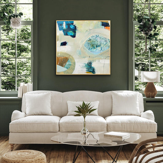 Living room with a white sofa, abstract AAlison Gilbert canvas print 'Beachcombing', and decorative items.