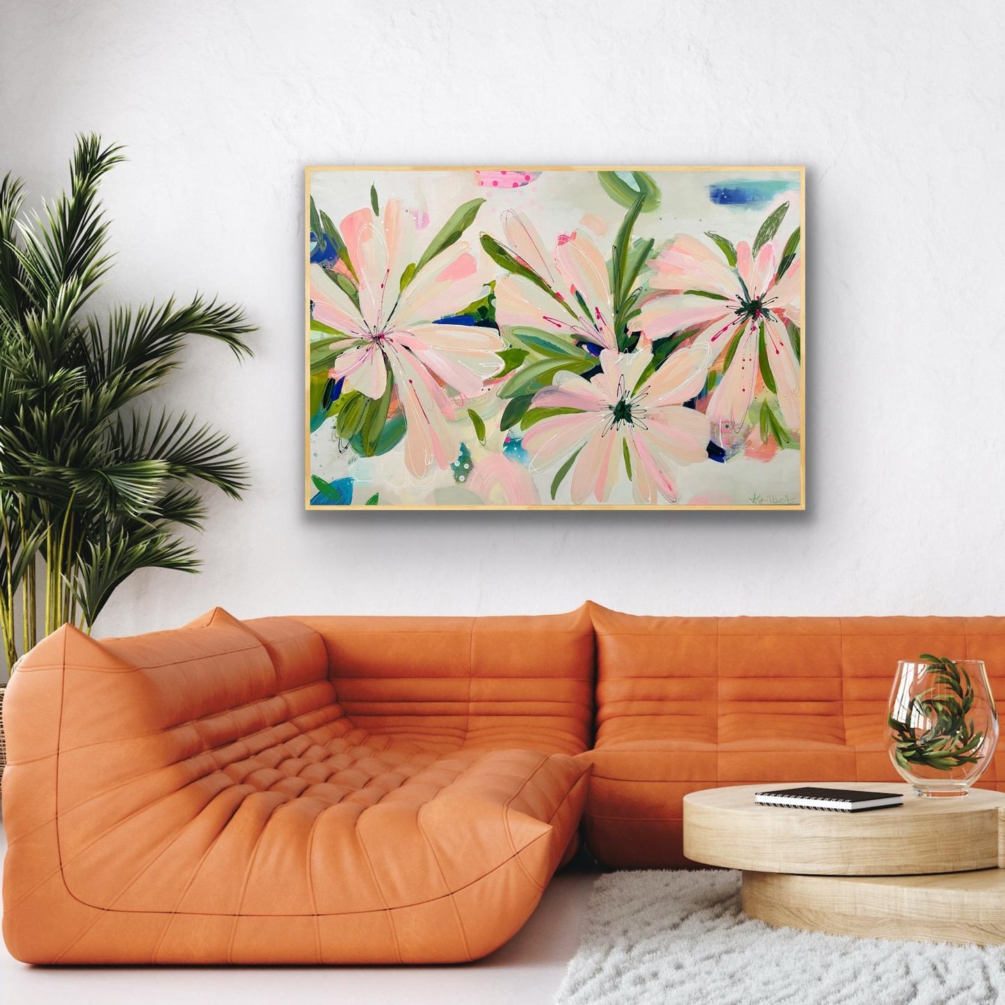 Orange sofa in a living room with a floral canvas print 'Bellini Blooms' on the wall.