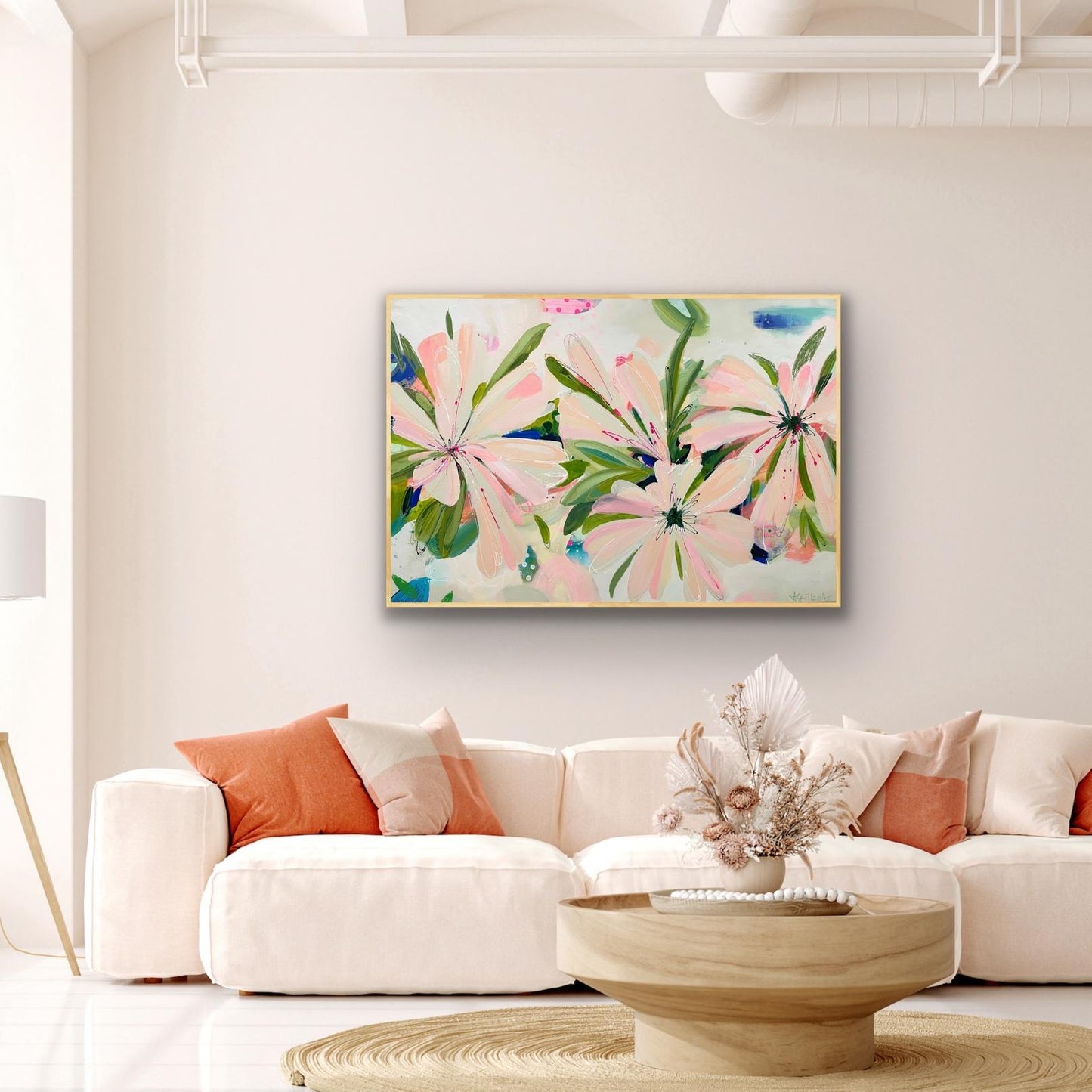 Floral Canvas Art Print 'Bellini Blooms' on a wall above a white sofa with colorful cushions in a living room.
