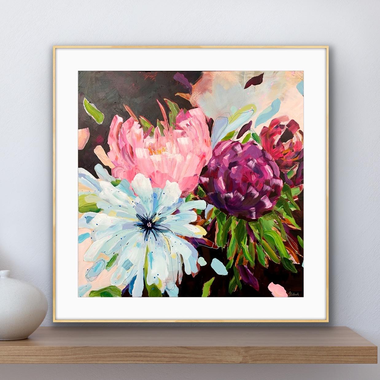 Framed floral wall art from alison gilbert art .com hanging on a light gray wall above a wooden shelf, showing an expressive painting of pink, purple, white, and green flowers with a white mat and thin gold-toned frame.