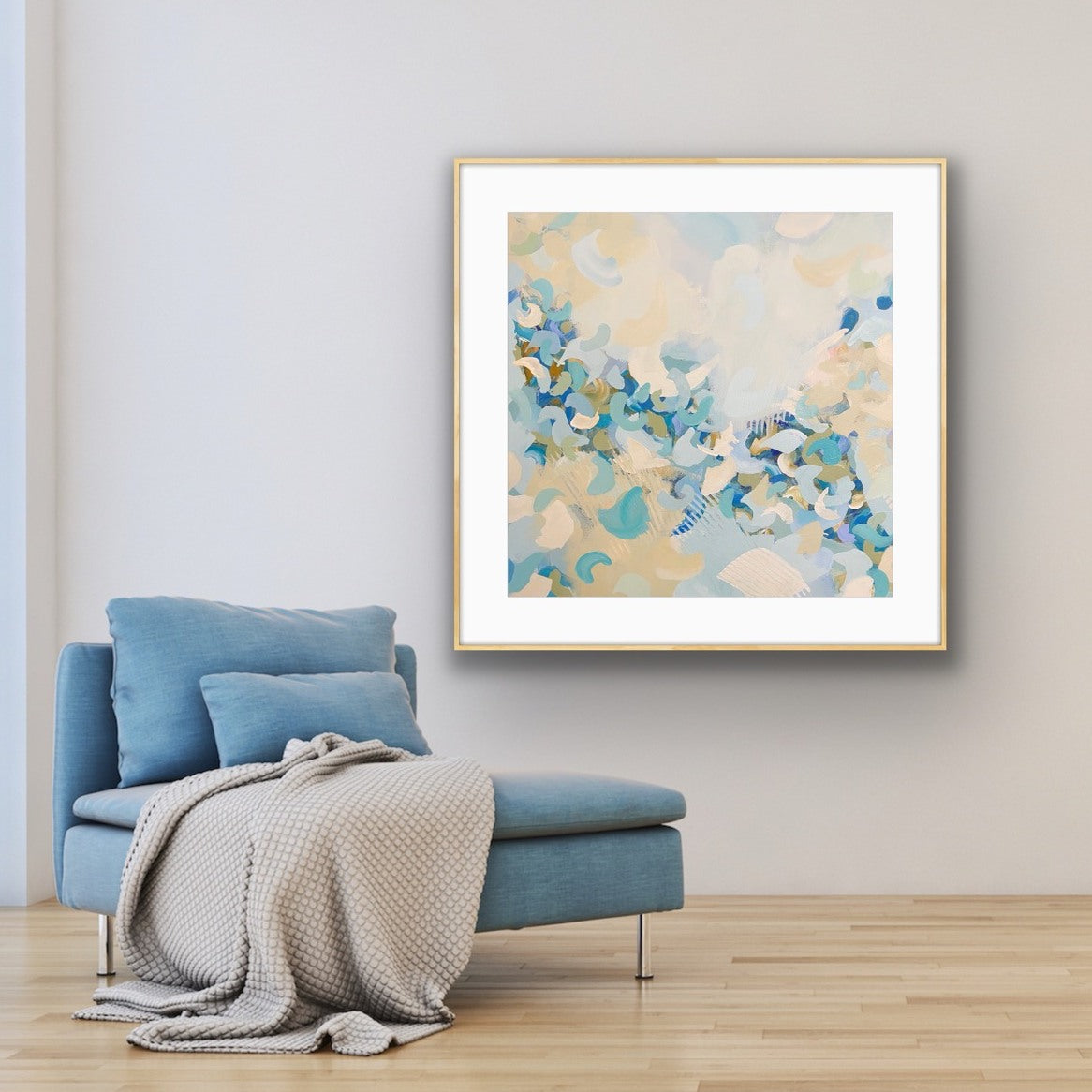 Framed abstract art print "BlueBlossom" above a blue armchair in a room with light-colored walls.