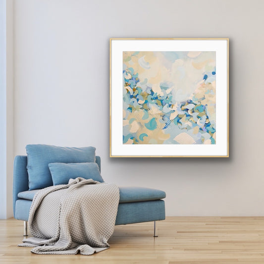 Framed abstract art print "BlueBlossom" above a blue armchair in a room with light-colored walls.