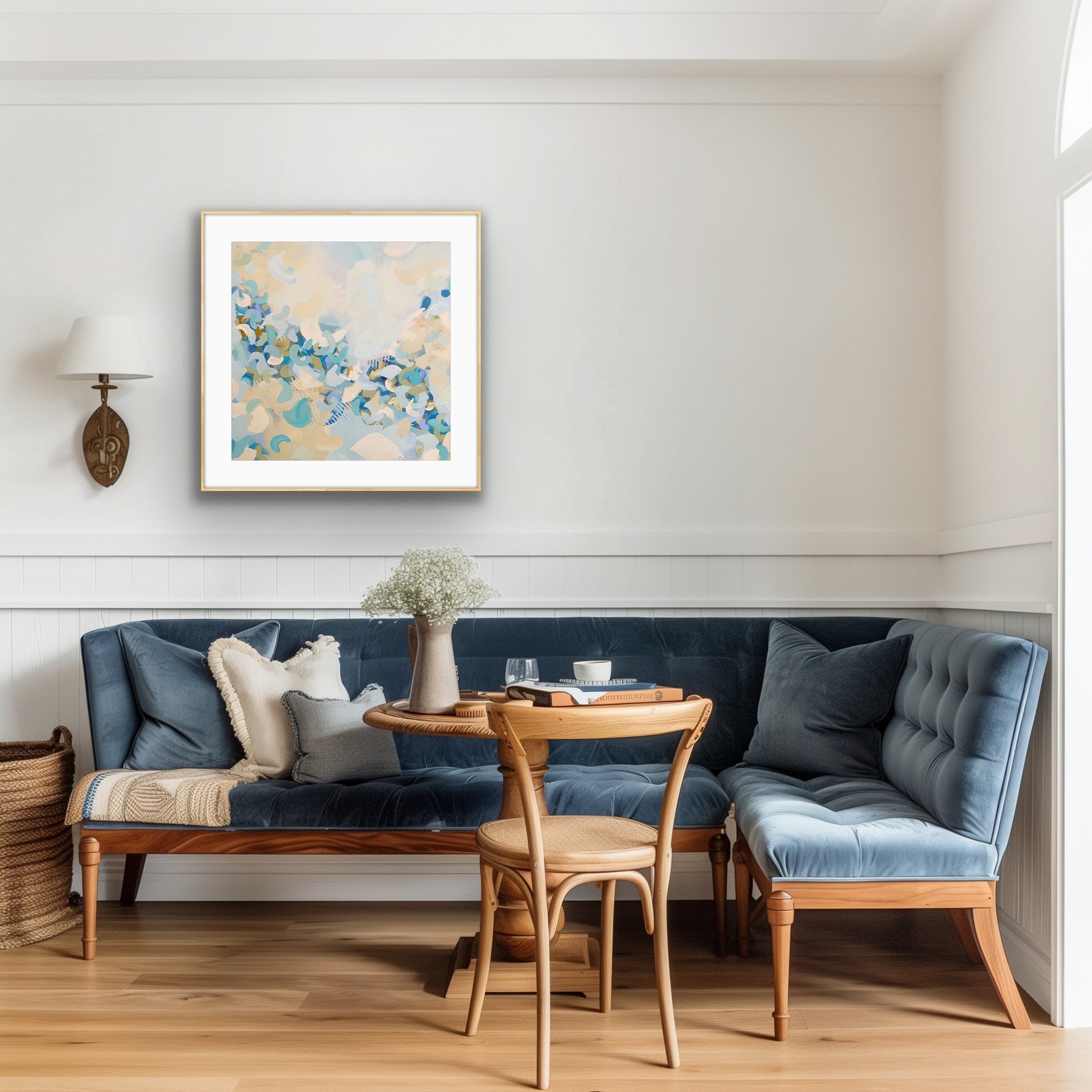 Living room with blue sofa, wooden chair, and light blue abstract art print "Blue Blossom" on the wall.