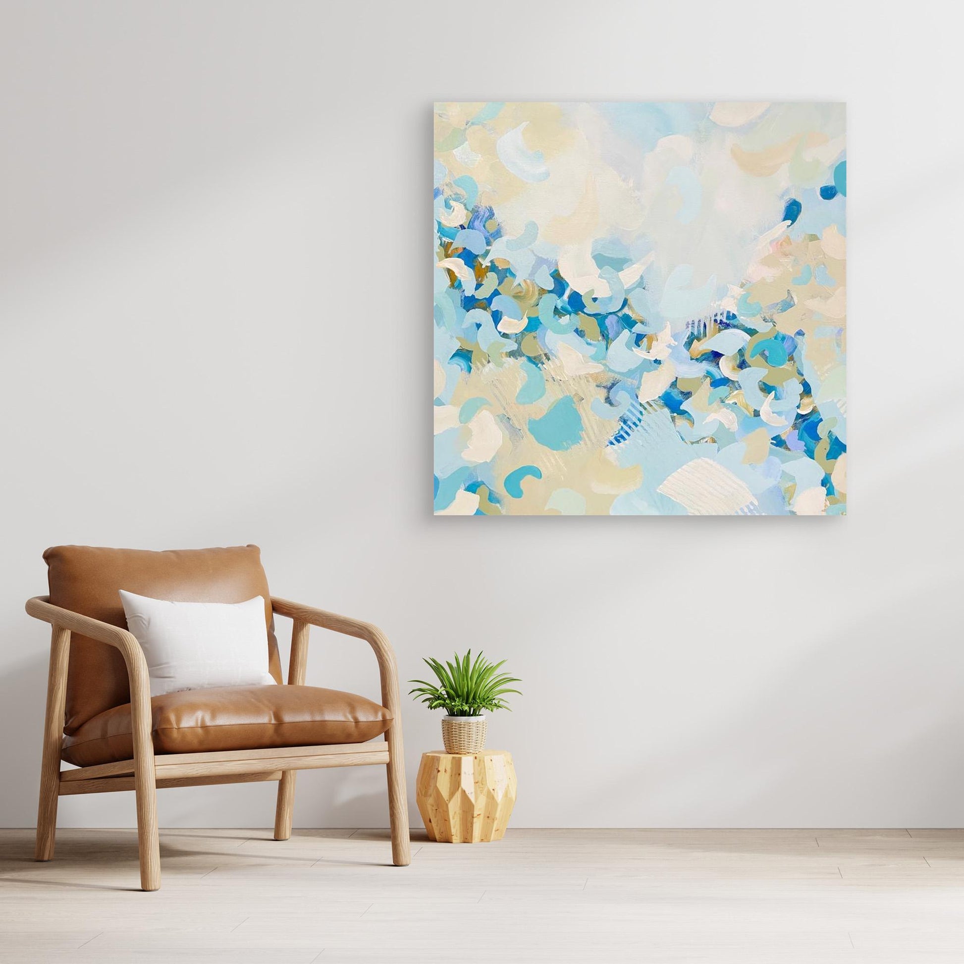 Abstract canvas print 'Blue Blossom' from Alison Gilbert in a modern living room with a brown chair and plant. 