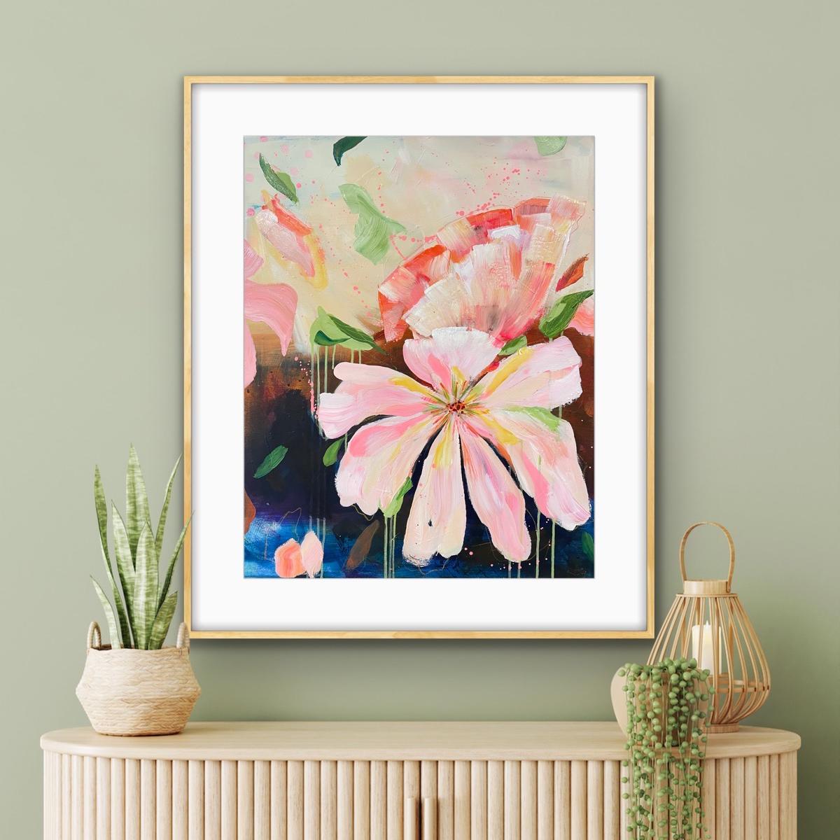 Framed floral print 'Botanical Dream' on a wall with decorative items below.