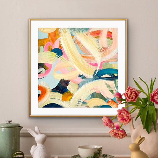 Colorful abstract print by Alison Gilbert Art on a wall above a wooden table with decorative items.