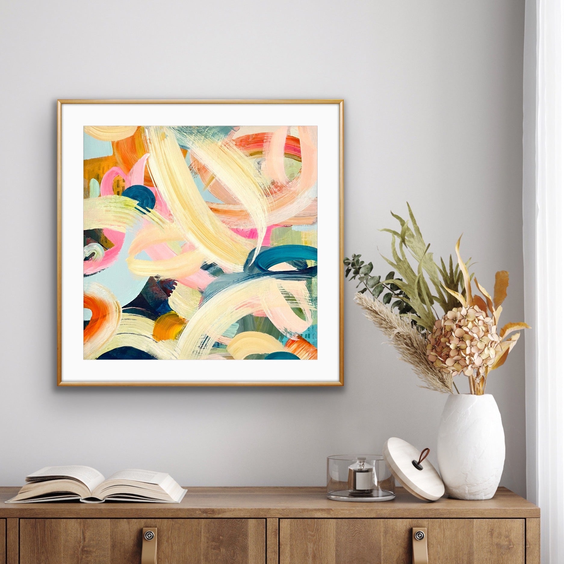 Abstract art print "Freewheeling" by Alison Gilbert Art, on a wall above a wooden cabinet with decorative items.