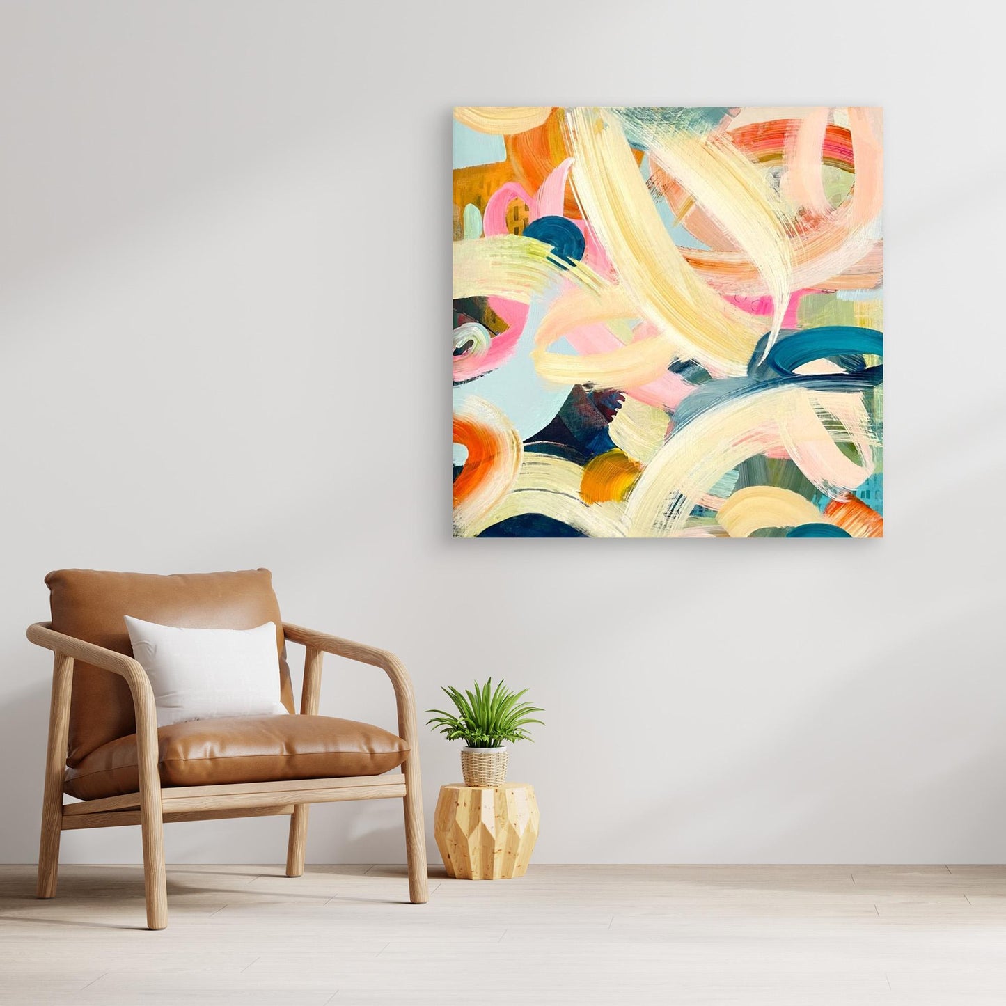Abstract Alison Gilbert canvas print 'Freewheeling' on a wall above a brown armchair with a plant on a wooden side table.