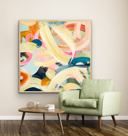 Colorful abstract Alison Gilbert canvas print 'Freewheeling'on a wall above a green armchair in a living room.