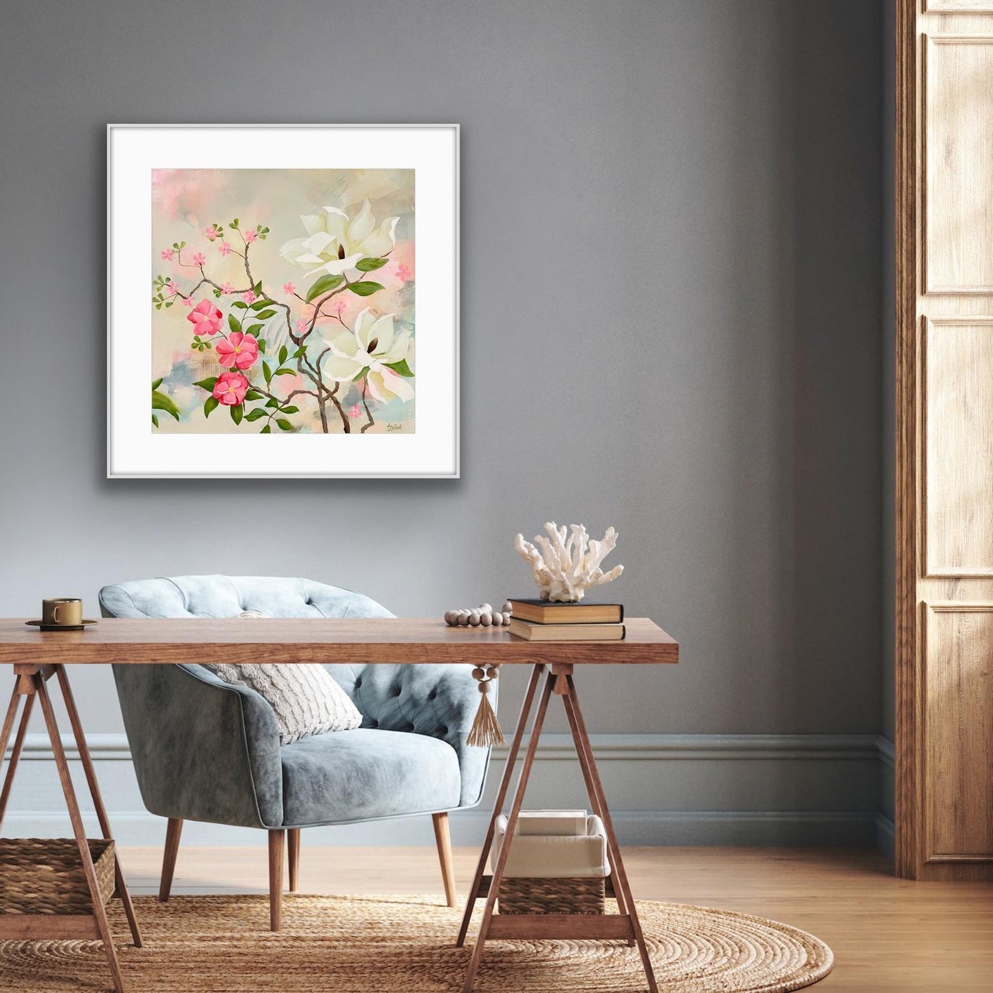 Framed floral Print 'Maytime Magnolias' artwork on a gray wall above a wooden desk with a chair.