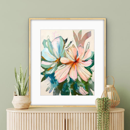 Framed abstract floral print of peach  propped on a console with potted plants