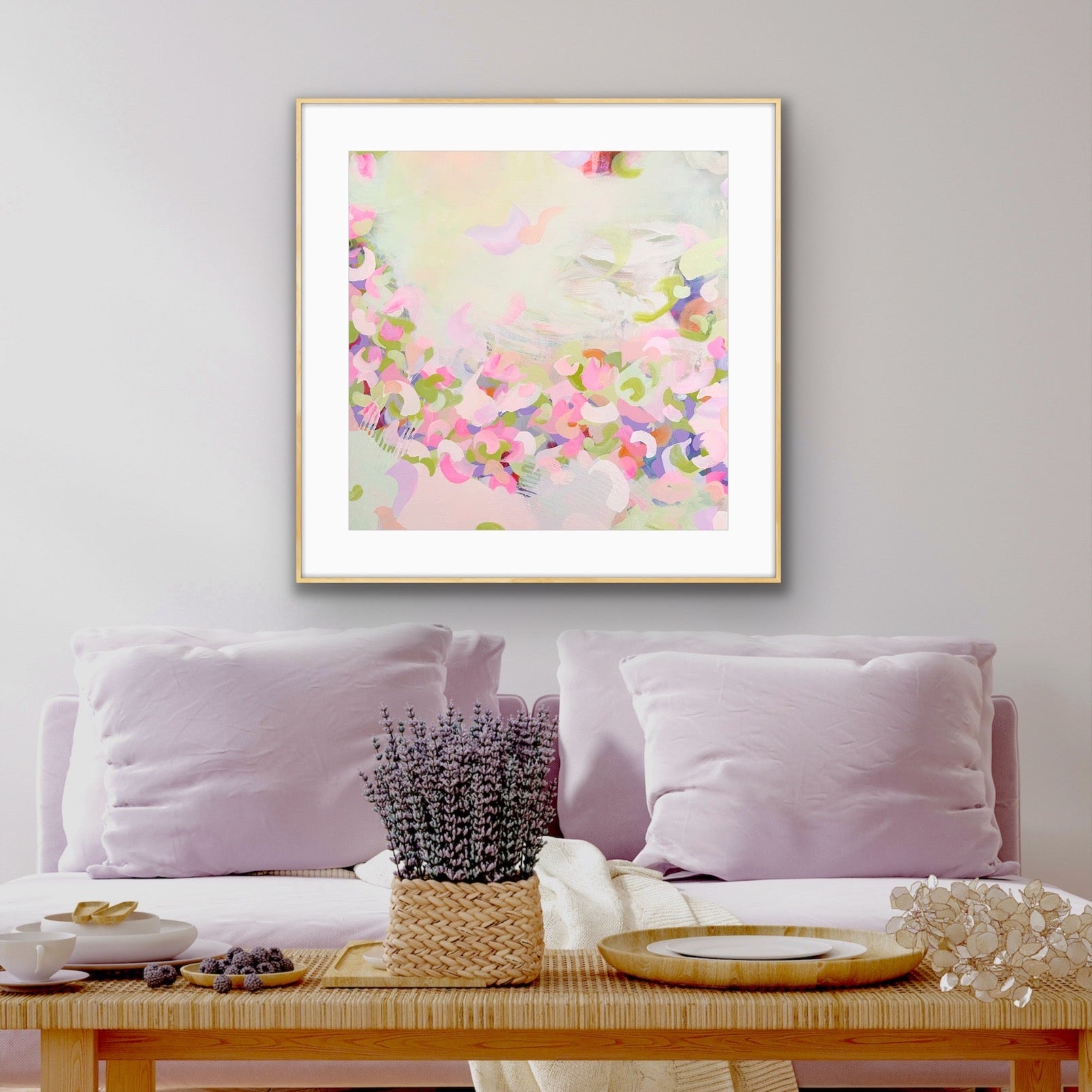 Framed pastel coloured abstract art print "Spring Serenade" by Alison Gilbert Art, on a wall above a sofa with decorative items.rt