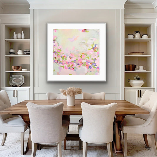 Dining room with a wooden table and white chairs, featuring a soft pastel coloured abstract print on the wall.