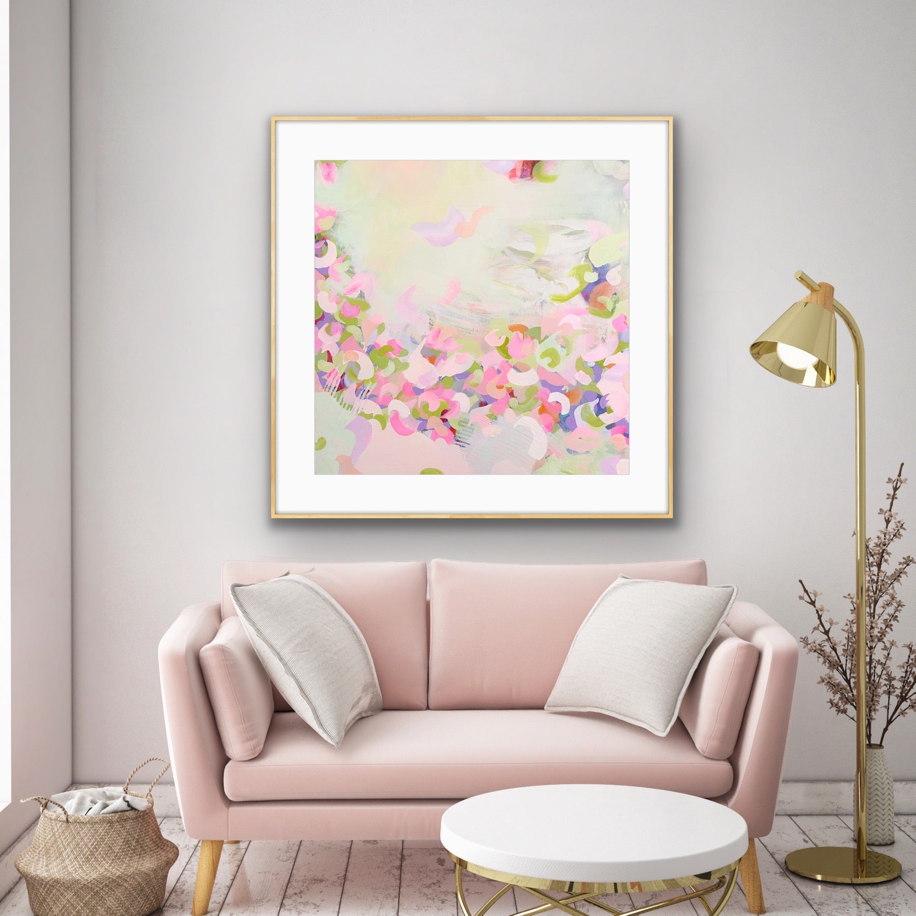 Living room with a pink sofa, pastel abstract art print "Spring Serenade" on the wall, and a gold floor lamp.