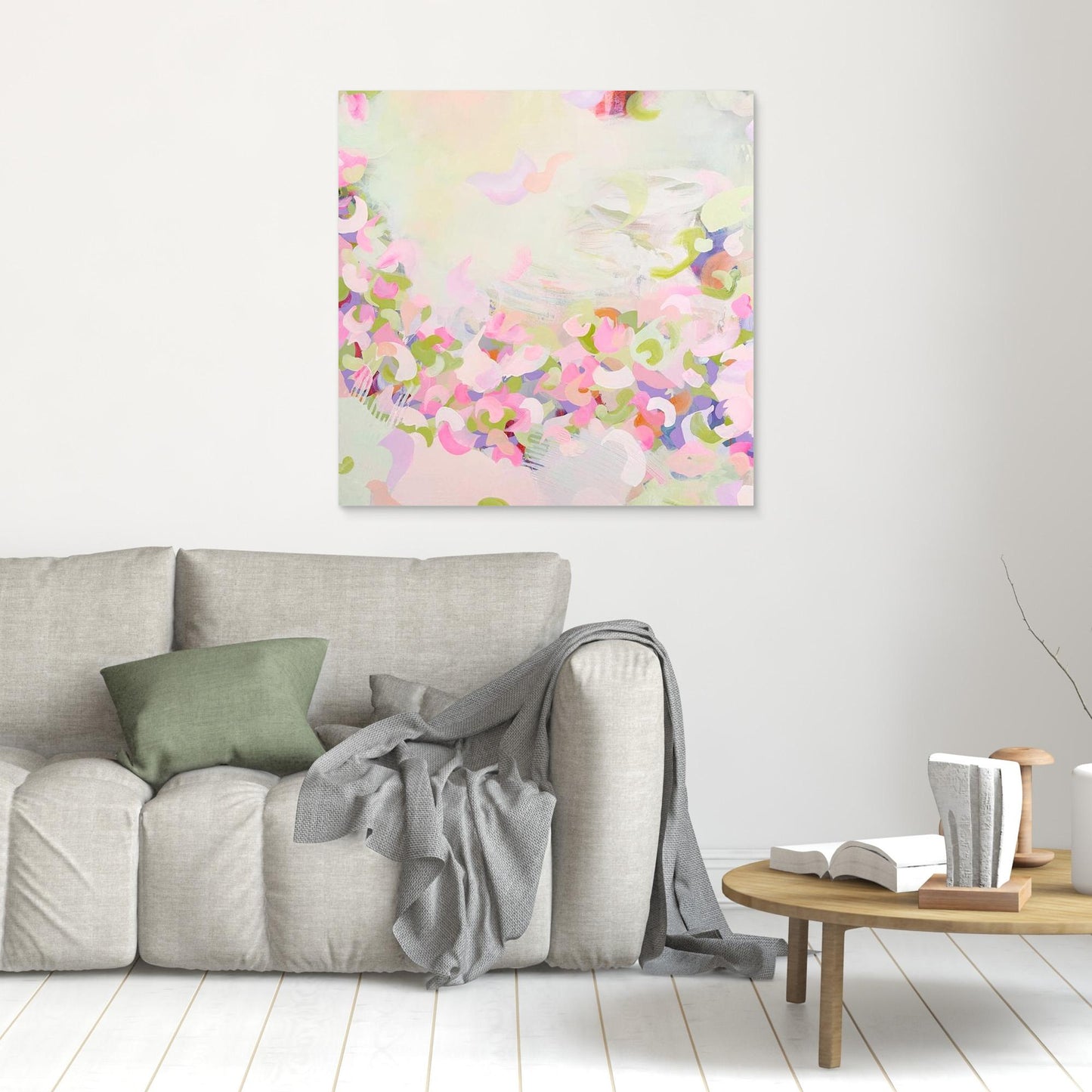 Framed pink abstract canvas print 'Spring Serenade' on a wall above a grey sofa.