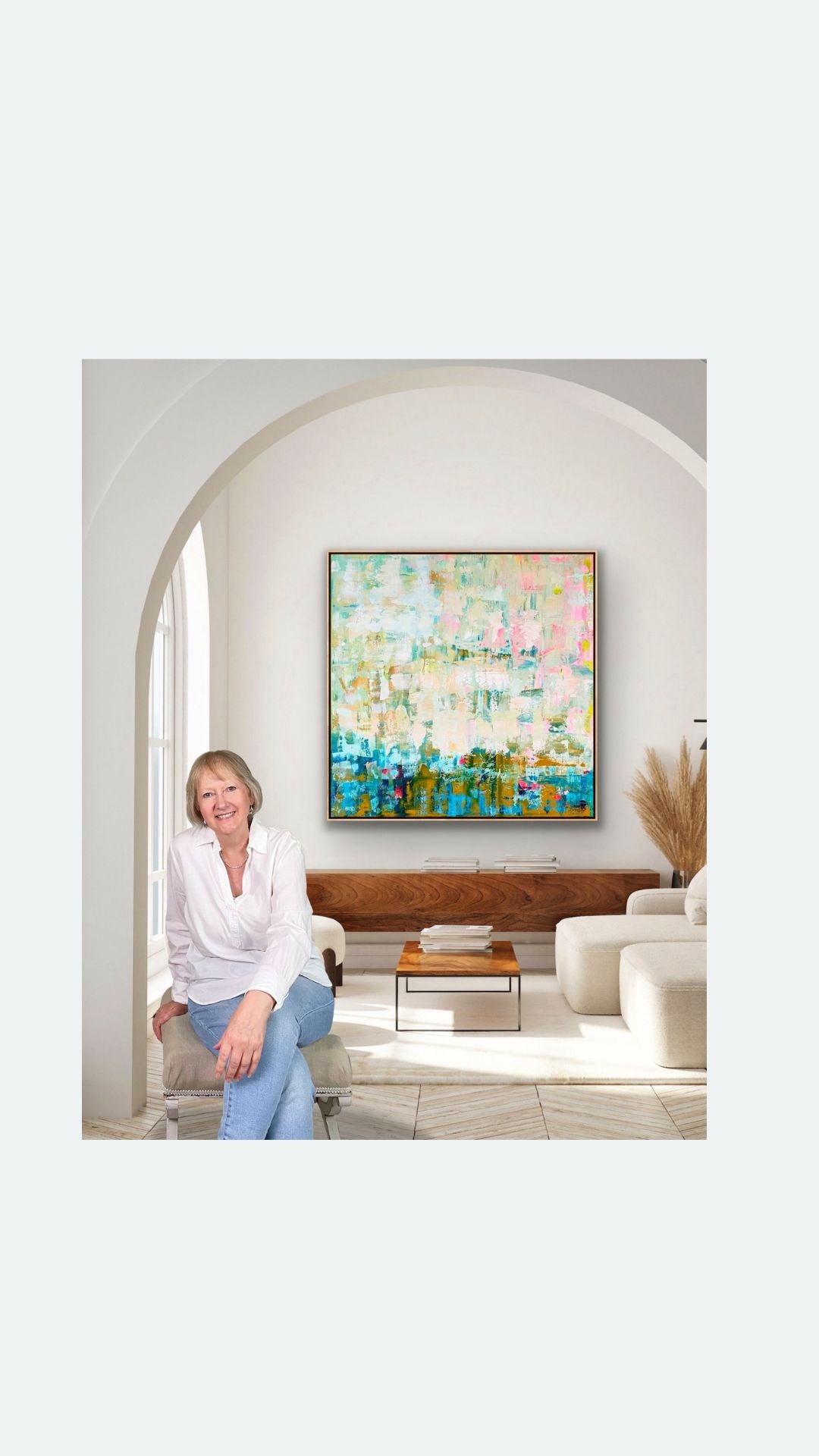 Woman sitting on a couch in a living room with a framed abstract canvas print "Where the Light falls' by Alison Gilbert on the wall.