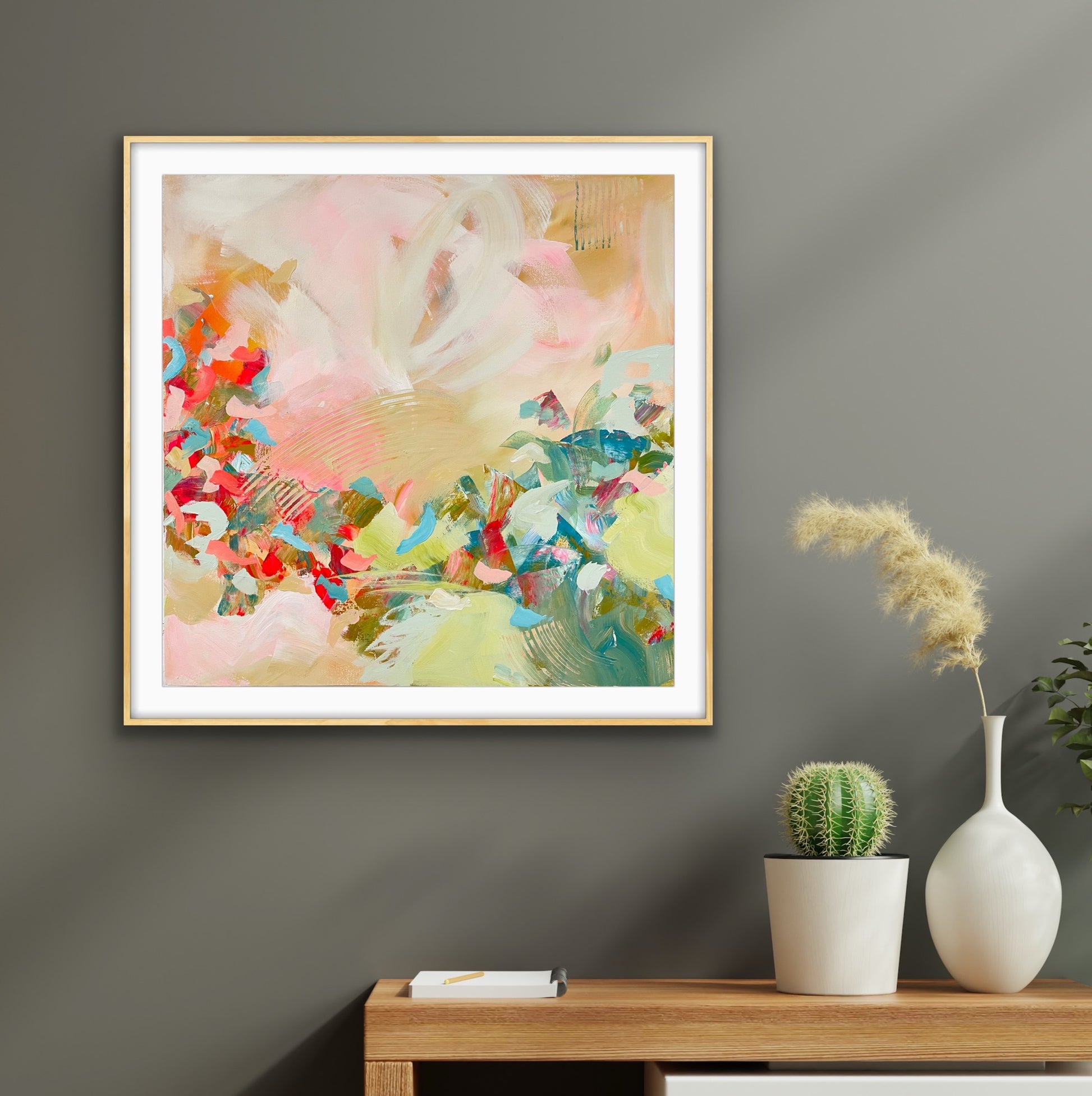 Framed abstract art print "Whispers of a New Day" on a wall with a table and decorative items below.