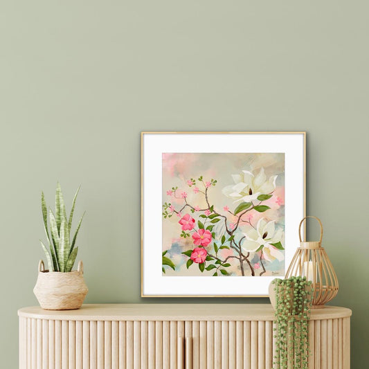 Framed floral artwork on a wooden cabinet with plants against a green wall